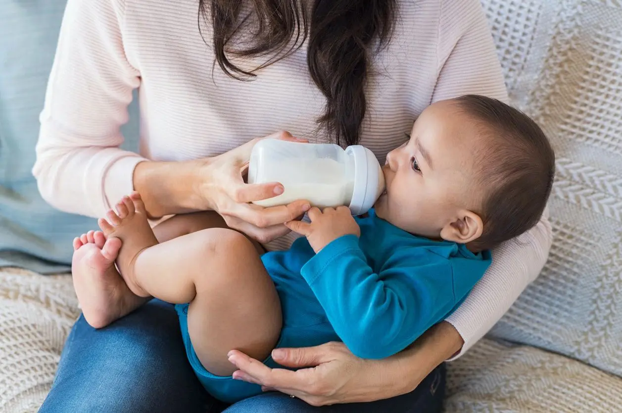 A woman is feeding her baby with a bottle.